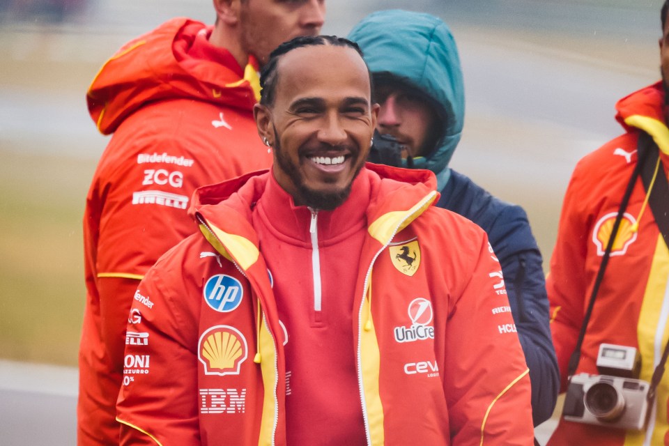 Lewis Hamilton smiling in a Ferrari jacket.