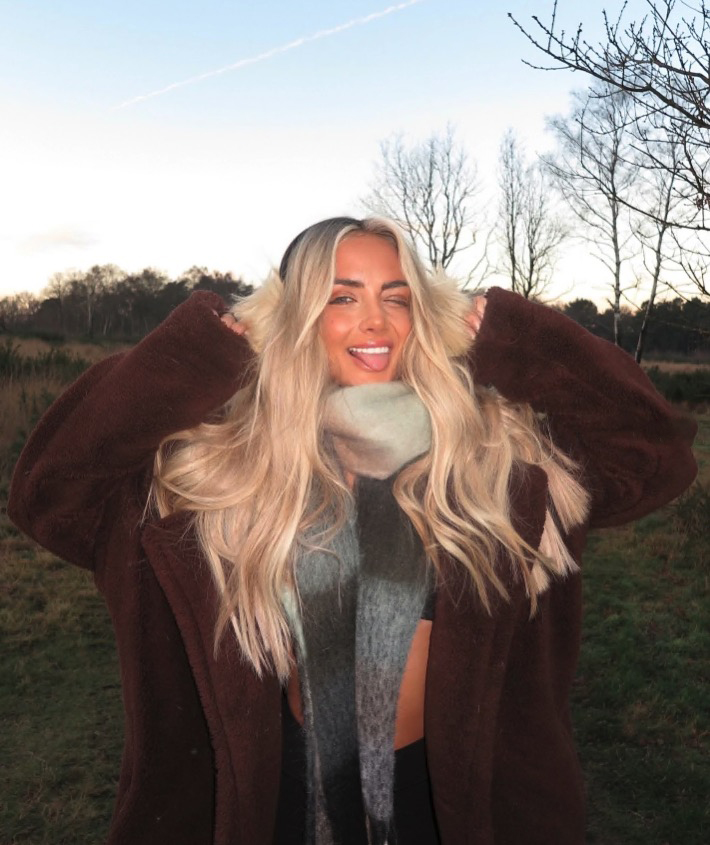 Woman in brown coat sticking out tongue.