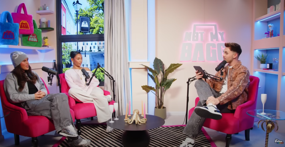 Three people sitting in pink chairs during a podcast interview.