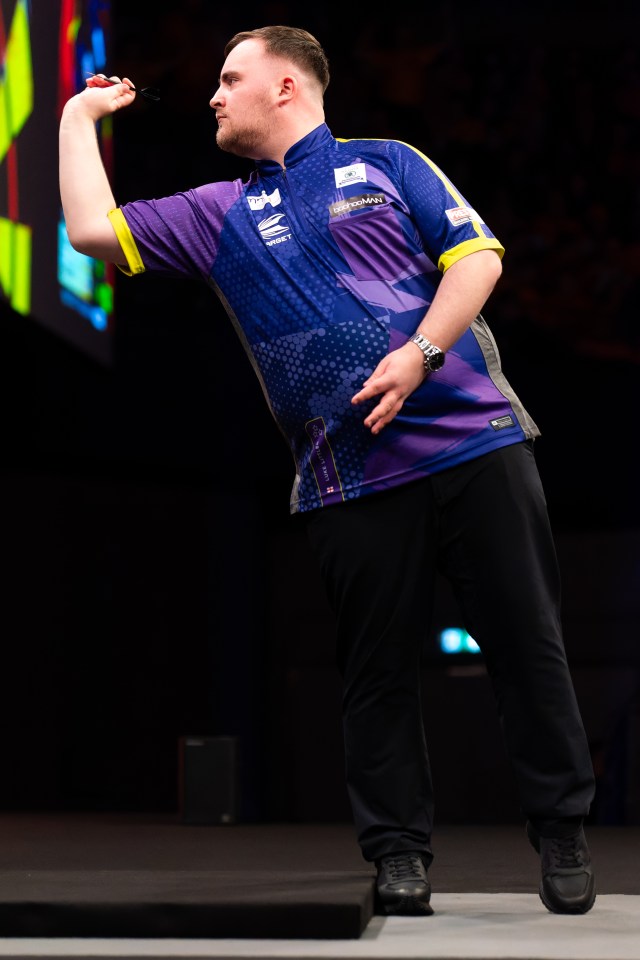 Luke Littler throwing a dart at a darts competition.