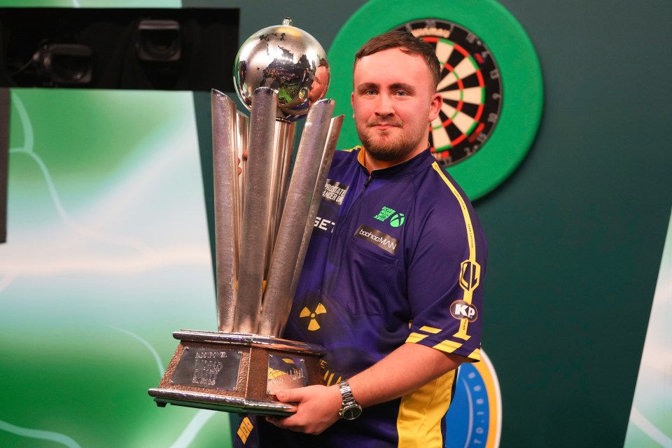 Luke Littler of England holding the World Darts Championship trophy.