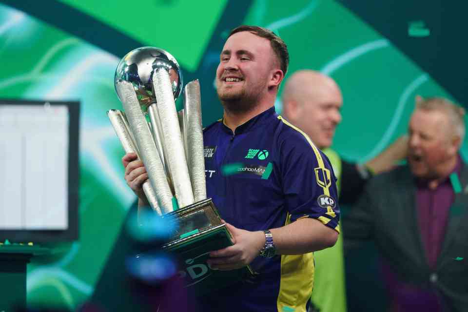 Luke Littler holding the Paddy Power World Darts Championship trophy.