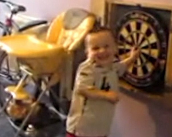 Toddler in a Steven Gerrard England kit standing near a dartboard.