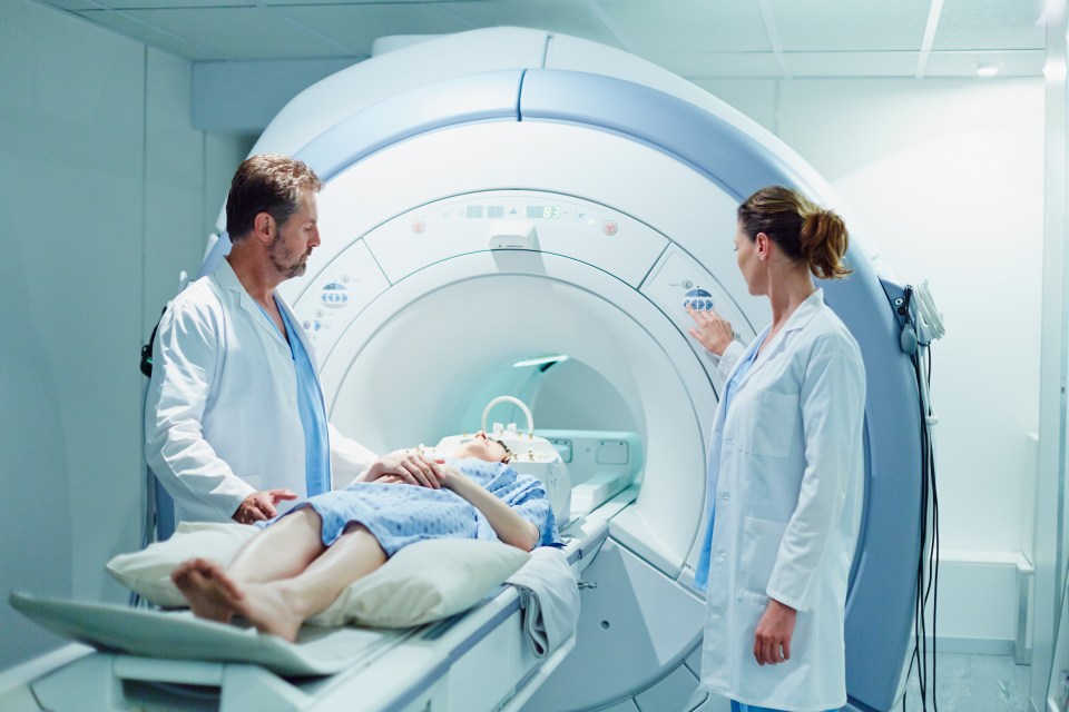 Two doctors prepare a patient for an MRI scan.