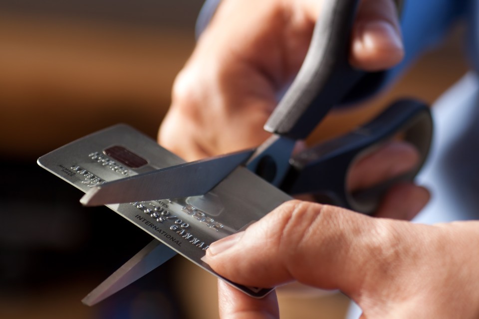 Hands cutting a credit card with scissors.