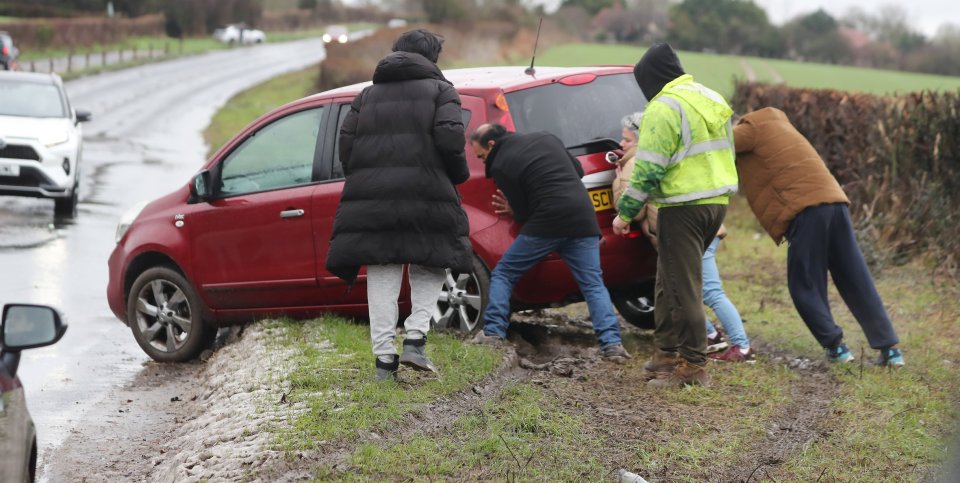 People push a stranded car in Essex