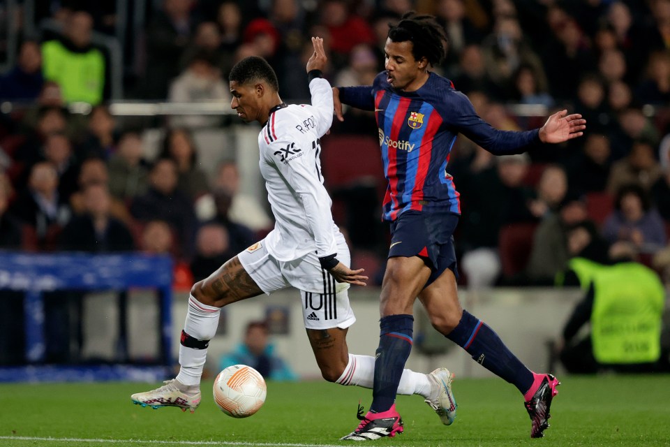 Marcus Rashford of Manchester United and Jules Kounde of FC Barcelona competing for the ball during a soccer match.