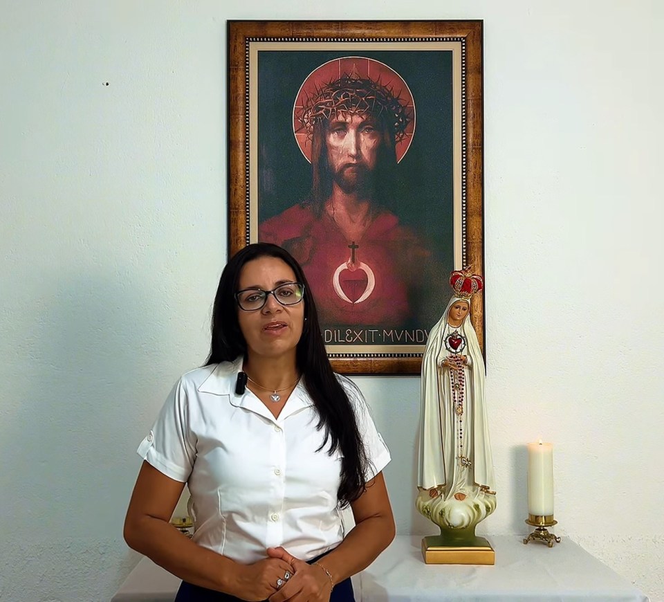 Woman in white shirt standing in front of religious images.