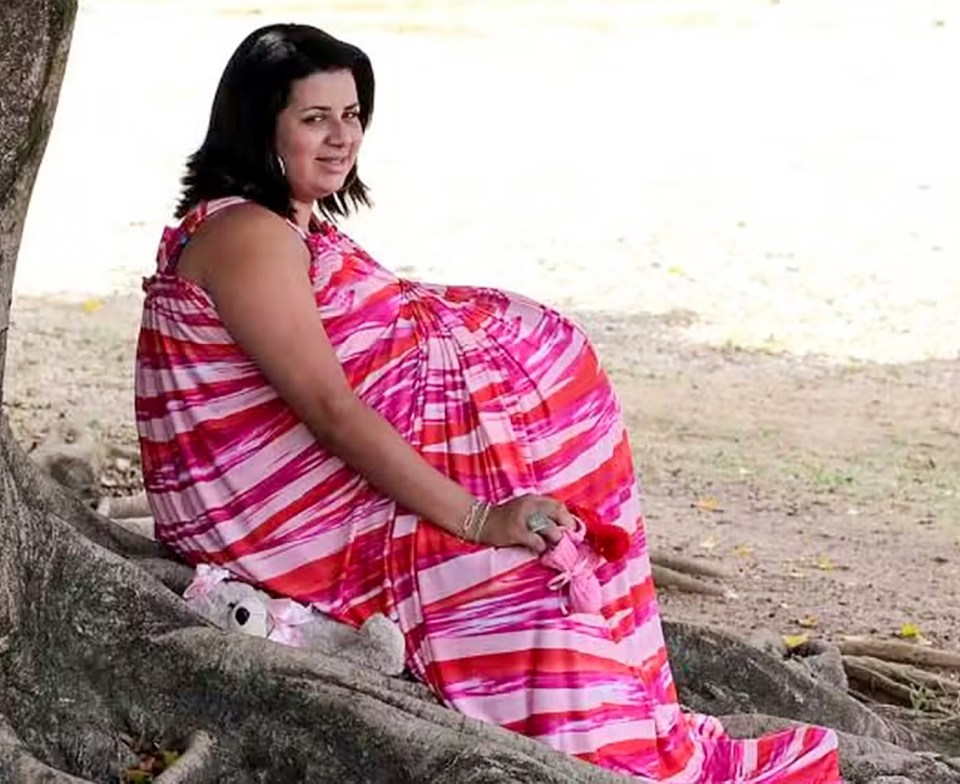 Woman in pink and red striped dress pretending to be pregnant.