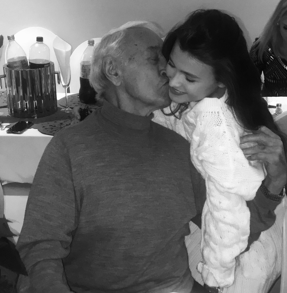 Black and white photo of a young woman kissing an older man on the cheek.