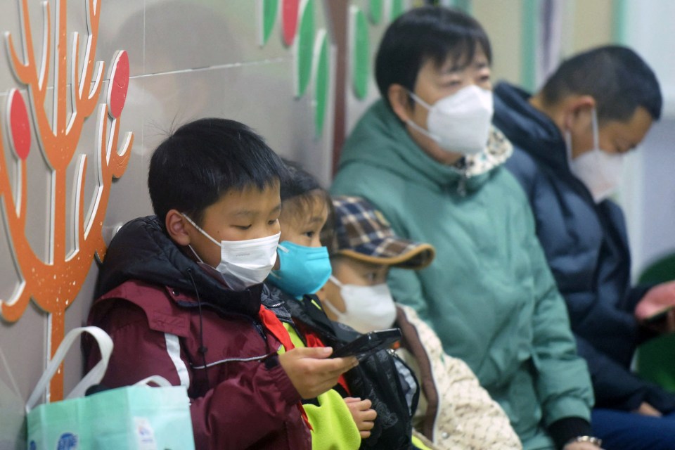 Masked children and adults wait in a hospital.