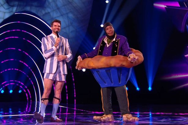 The Masked Singer contestant dressed as a giant cupcake stands with a host.