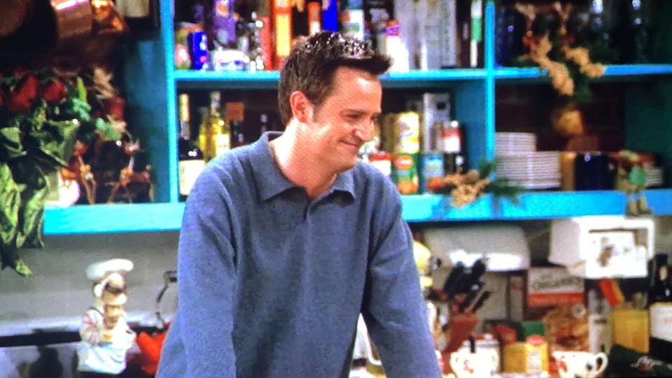 Matthew Perry as Chandler Bing in a blue sweater.