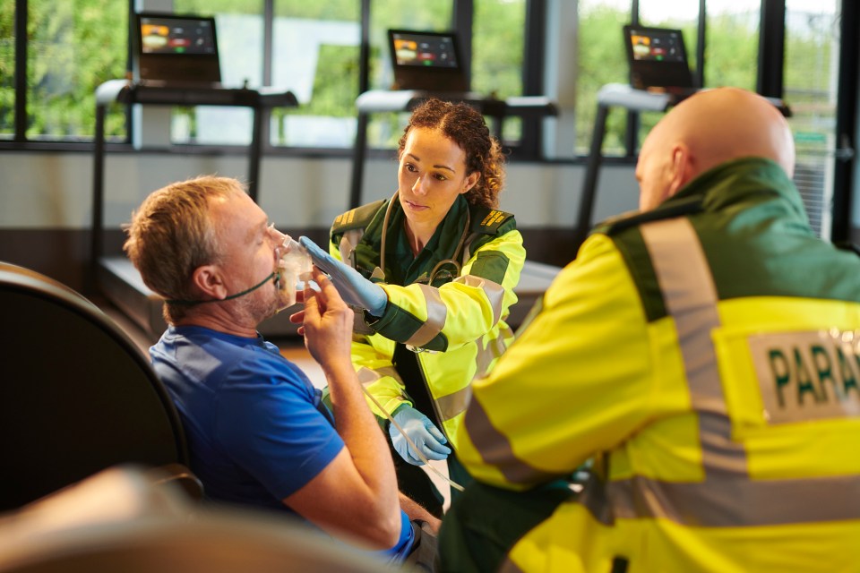 Paramedics assisting a man in a gym.