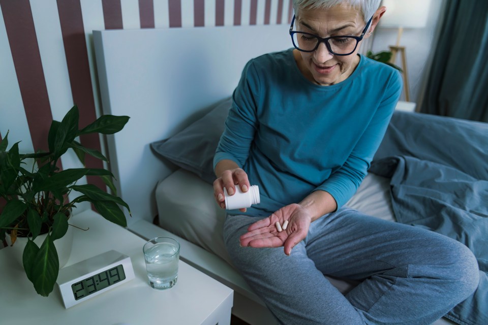 Woman taking melatonin pills before bed.