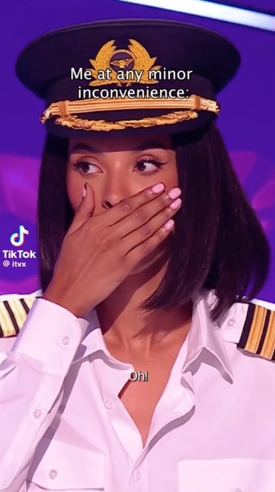 Maya Jama in a pilot's uniform reacting to a minor inconvenience.