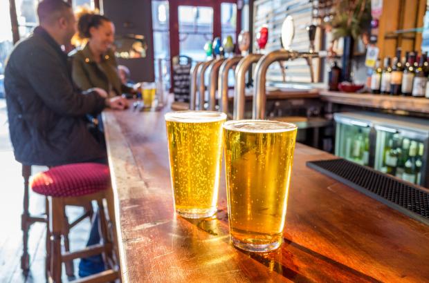 Two pints of lager on a pub bar.