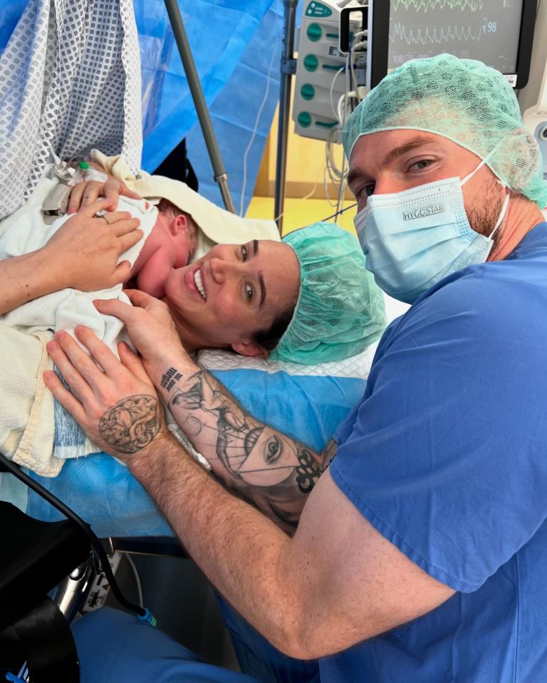 New parents holding their newborn baby in a hospital room.