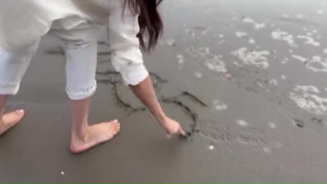 Meghan Markle drawing in the sand on a beach.