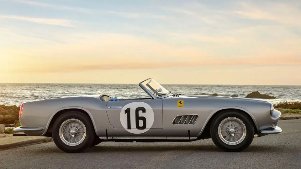 Silver Ferrari 250 GT California Spider convertible, number 16, by the ocean.