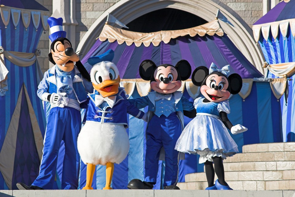 Mickey, Minnie, Goofy, and Donald Duck in blue costumes on stage.