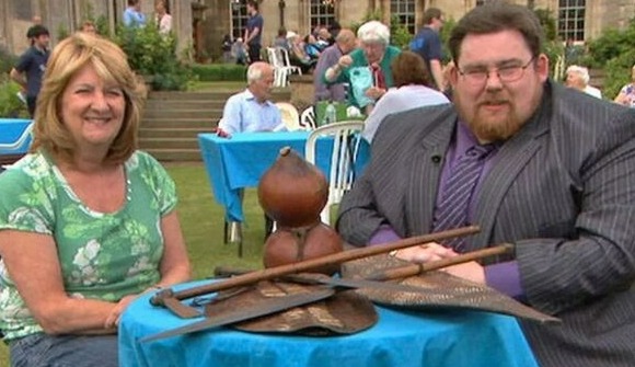 Two people sitting at a table with African artifacts.