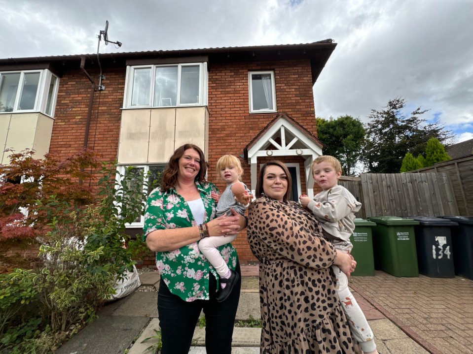 Family of four posing in front of their house.