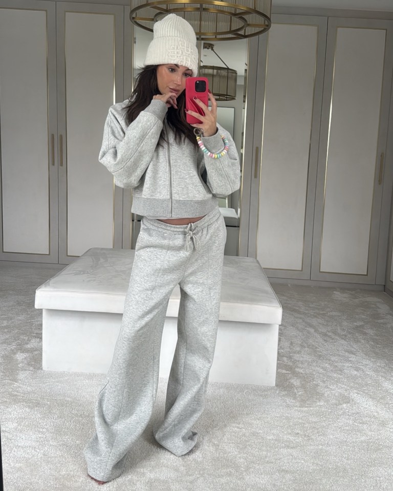 Michelle Keegan in a grey tracksuit and white beanie, taking a selfie.