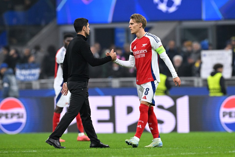 Mikel Arteta and Martin Odegaard shaking hands after a soccer match.