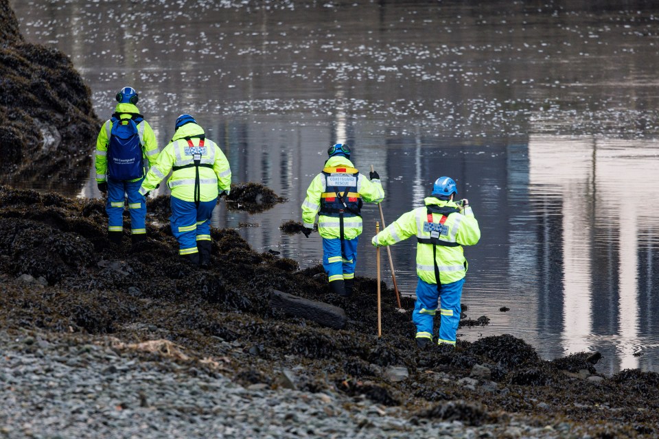 Police and coastguard officers searching near a river.