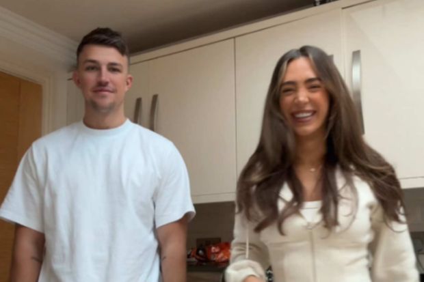 A man and woman smiling in a kitchen.