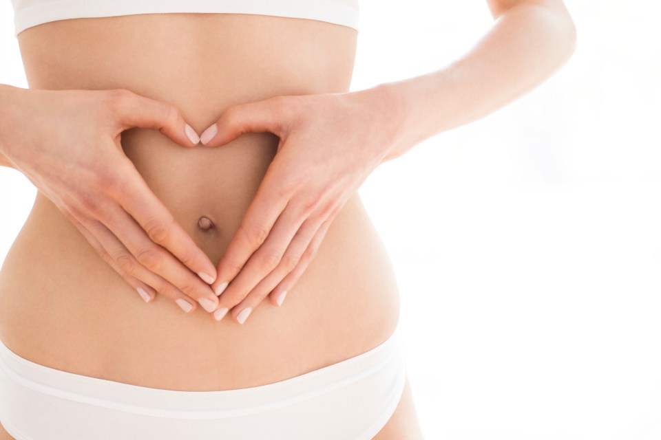 Woman's hands forming a heart shape on her abdomen.