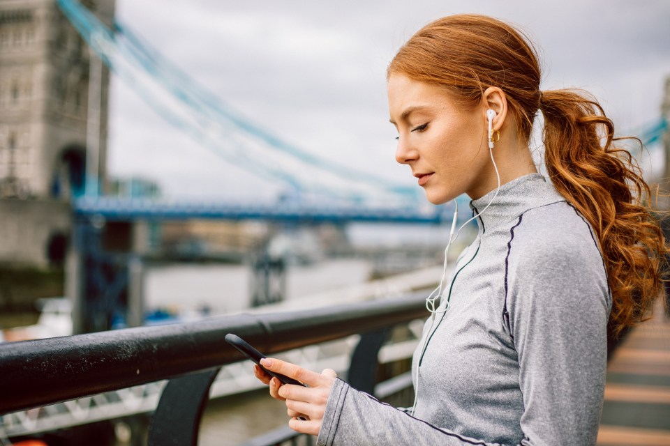 Woman using phone while wearing earphones.