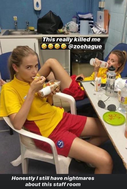 Two young women in lifeguard uniforms eating in a messy staff room.