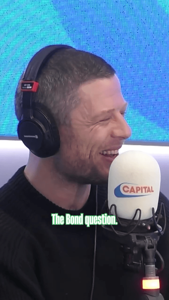 James Norton smiling while wearing headphones and speaking into a Capital radio microphone.