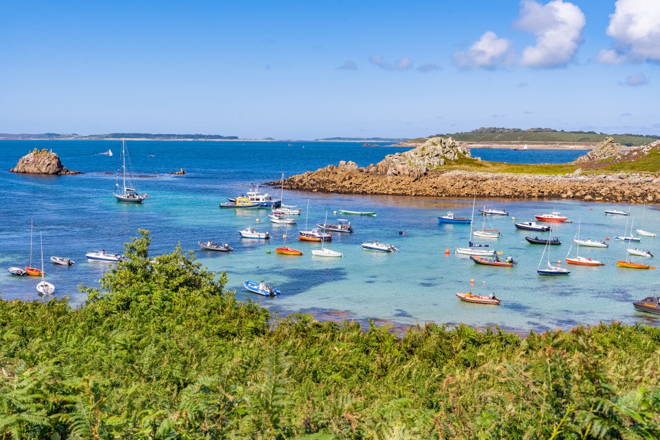 Numerous boats moored in a calm, turquoise bay near St Agnes Island.