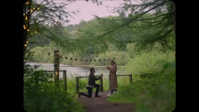 Man proposing to woman by a lake.