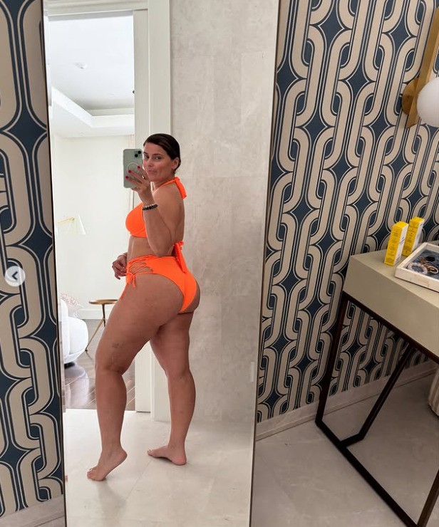 Woman in orange bikini taking a selfie in a mirror.