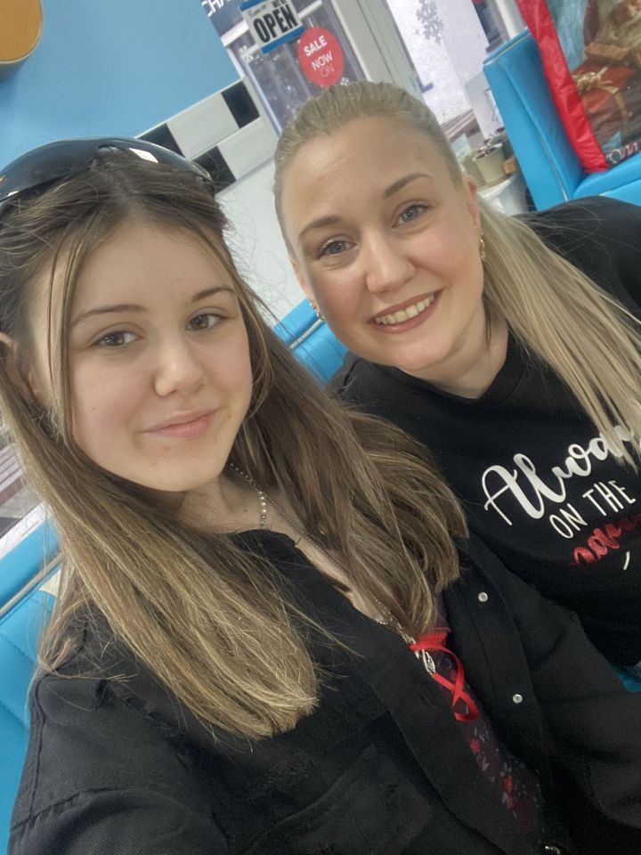 A mother and her teenage daughter pose for a selfie.