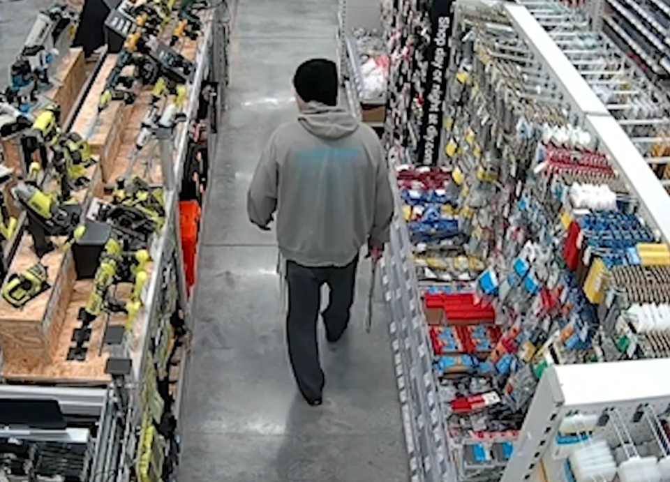 Surveillance image of a man walking in a hardware store aisle.