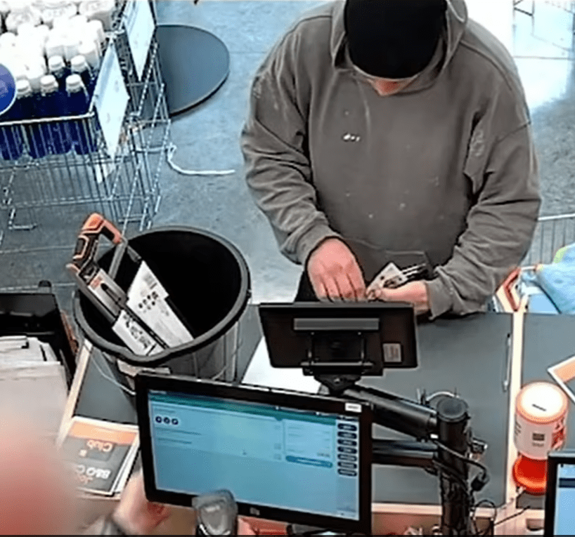 Surveillance image of a person paying at a checkout counter.