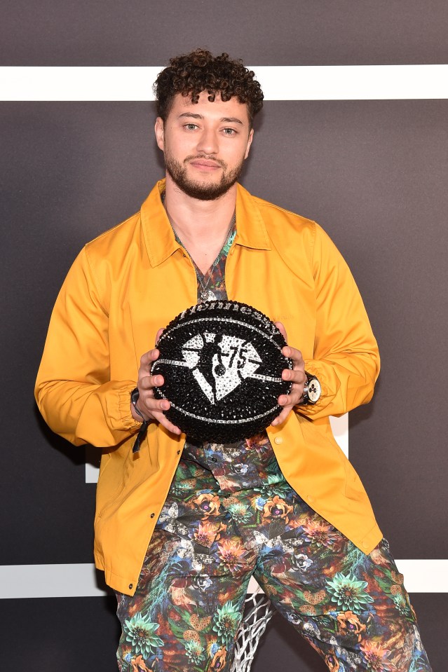 Myles Stephenson holding a jeweled basketball at an NBA event.