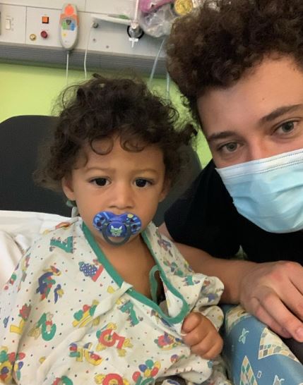 Toddler in hospital gown with older sibling.