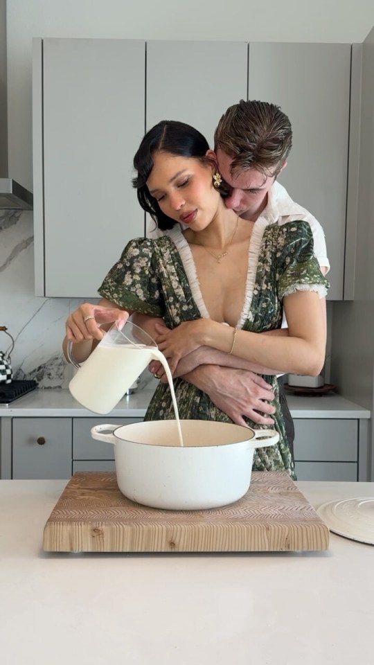 Couple pouring milk into a pot in a kitchen.