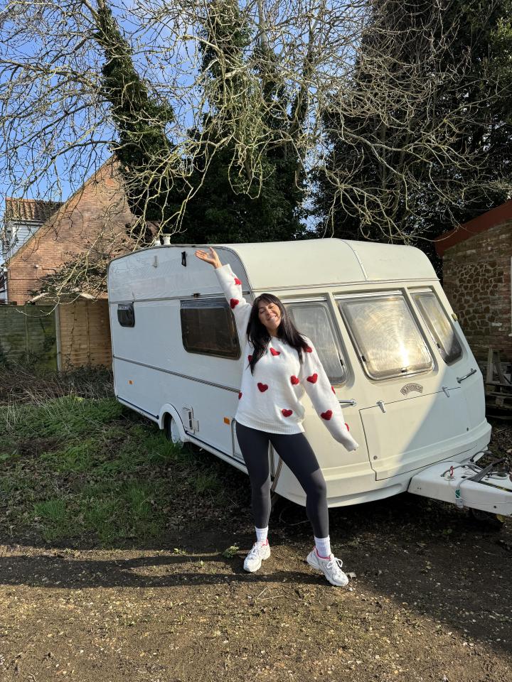 Woman standing next to a renovated caravan.