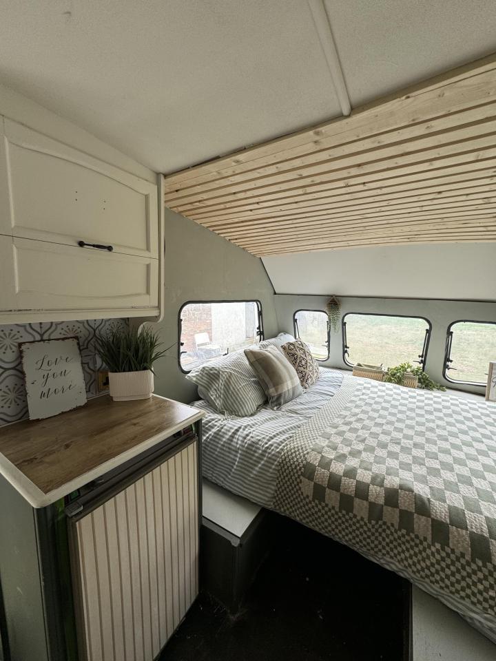 Renovated caravan interior with bed and kitchenette.