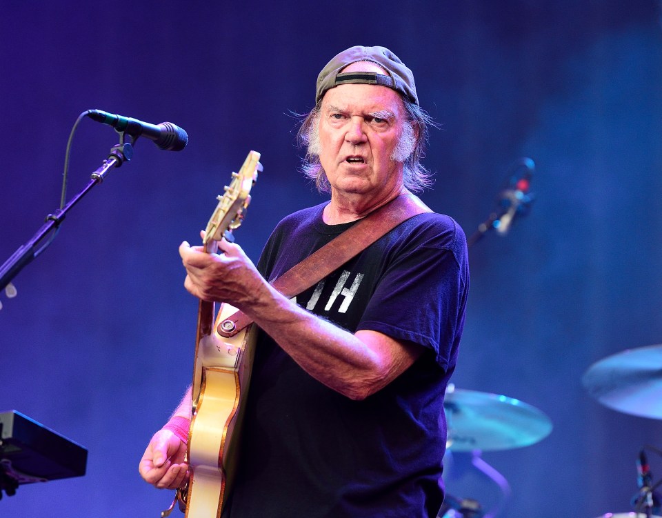 Neil Young performing on stage with Crazy Horse.