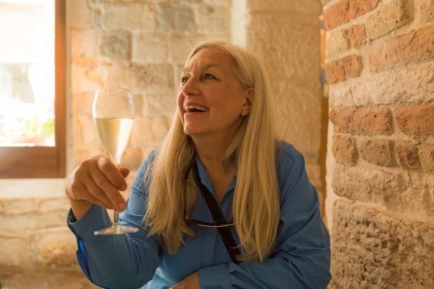 A woman holds a glass of champagne and smiles.