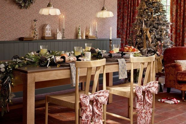 Christmas dining table setting with decorated chairs.