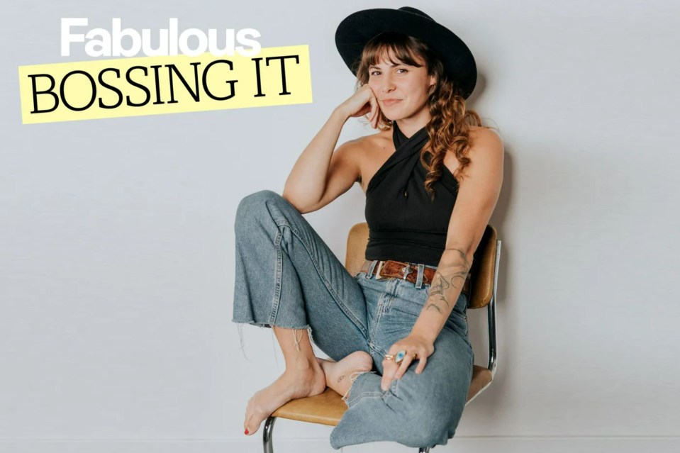 Woman sitting in chair, wearing jeans and a black top; text overlay: "Fabulous Bossing It"